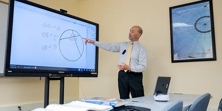 A Teacher doing a math problem on a projected screen